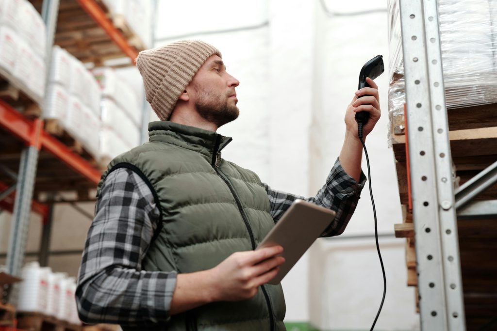 A man conducting a stock-checking process in a warehouse using technology to track inventory.